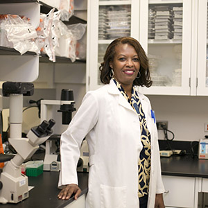 Deborah Culver standing in a laboratory in front of a microscope