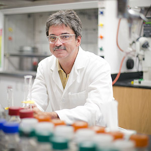 Dr. Lockwood sitting at a lab desk behind a row of beakers