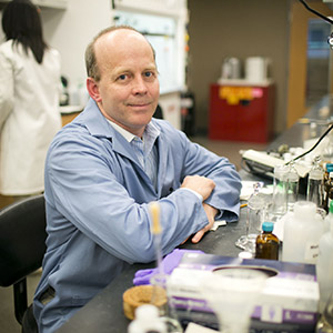 Dr Hager sitting at a lab desk surrounded by various apparatuses